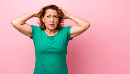 middle age hispanic woman feeling stressed, worried, anxious or scared, with hands on head,...