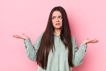 young adult woman shrugging with a dumb, crazy, confused, puzzled expression, feeling annoyed and...