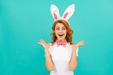 surprised easter girl in bunny ears and bow tie on blue background. copy space