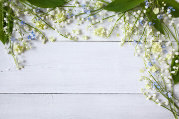 Spring lilies of the valley, forget me not flowers, viburnum flowers on a white wooden background, space for greeting text. Top view, copy space