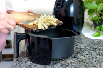 Putting sliced and frozen potatoes in the Airfryer for frying. Making healthy food without frying...