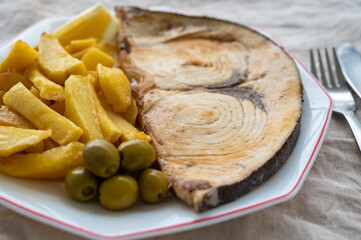 Seafood dish, grilled steak from swordfish or spada served with french fried potatoes and green olives