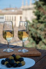 Tasting of Spanish sweet and dry fortified Vino de Jerez sherry wine and olives with view on roofs and houses of old andalusian town