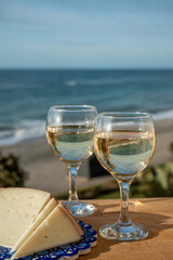 Spanish hard manchego, cow, sheep and goat cheese served outdoor with glasses of white wine and view on blue sea
