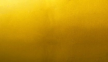 Gold wall texture background. Yellow shiny gold foil paint on wall sheet with gloss light reflection