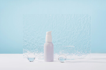 Cosmetic cream metallic pump bottle mockup on blue background with stylish props, glass balls and...