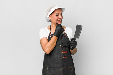 middle age woman smiling with a happy, confident expression with hand on chin. butcher concept