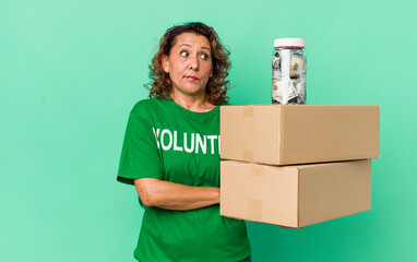 middle age woman shrugging, feeling confused and uncertain. volunteer and donation concept