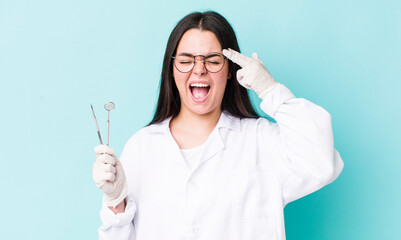 young adult woman looking unhappy and stressed, suicide gesture making gun sign. dentist concept