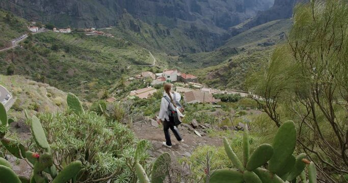 Masca Gorge and village on the island of Tenerife, Canary Islands, Spain. Young woman climbing a mountain, enjoys nature.