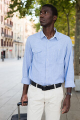 Portrait of an african american tourist on the street of european city with suitcase