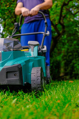  lawn mower mows the lawn in the summer garden.Technique and equipment for the garden. Summer work in the garden. A man cuts green juicy grass with a lawn mower in a garden