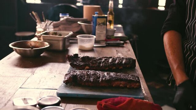 Chef in black gloves is preparing spare ribs. Video footage from the kitchen.