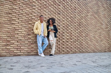 Obraz na płótnie Canvas Boy and girl looking at camera near brick wall