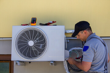 Photo of a plumber assembling and servicing the engine of a home air conditioner. Do-it-yourself...