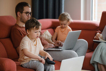 Big happy family watching movies playing games on laptop. Mother father kids spending time with gadgets on sofa Children with parents looking on computer screen at home Siblings playing with console