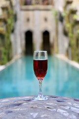 glass with red wine near the swimming pool in the tropics