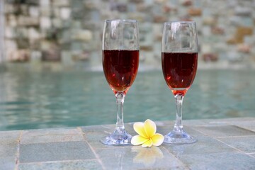 glasses with red wine near the swimming pool in the tropics