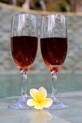 glasses with red wine near the swimming pool in the tropics