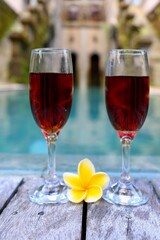 glasses with red wine near the swimming pool in the tropics