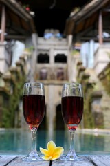 glasses with red wine near the swimming pool in the tropics
