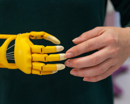 A woman demonstrates a plastic children's prosthetic hand printed on a 3D printer. 