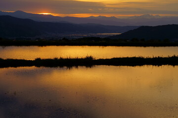 田植え前の水田の水に映り込む山里の夕景
