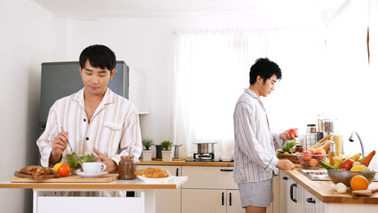 Happy gay couple enjoy breakfast in kitchen drinking coffee. Two best friends LGBTQ relation partner home cooking. Happiness romance homosexual marriage lifestyle. Two men together love friendship.