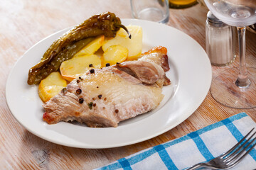 Close up of tasty baked pork with potatoes, served on plate