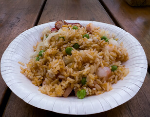 Angle view of special large Chinese asian egg and vegetable fried rice on a eco paper plate on the wooden table Background. Environmental friendly concept.