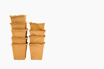 Pile of square brown fibre pots used to assist in the speedy germination and growth of seeds into plants on white background,fibre pots. Ecologic biodegradable material concept.