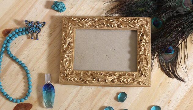 Blue Jewelry and Peacock Feathers With Gold Picture Frame on Wooden Table