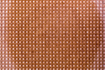 Background and texture of a surface of a confectionery waffle of brown color