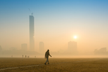 Morning walker walking past Kolkata maidan, at sunrise in a foggy winter morning. Sunrises at the...