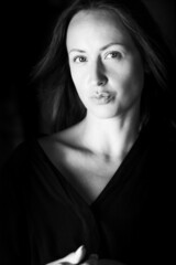 Black and white photo of an attractive woman. A large portrait on a dark background. Vertical photo.