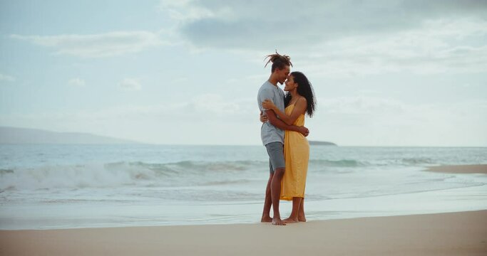 Romantic young black couple in love sharing special moment on the beach at sunset