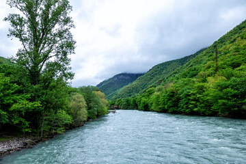 Fototapeta premium Mountain river and forest covered with low overcast clouds