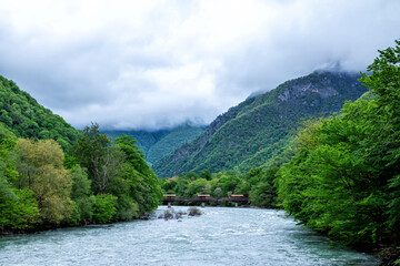 Mountain river and forest covered with low overcast clouds