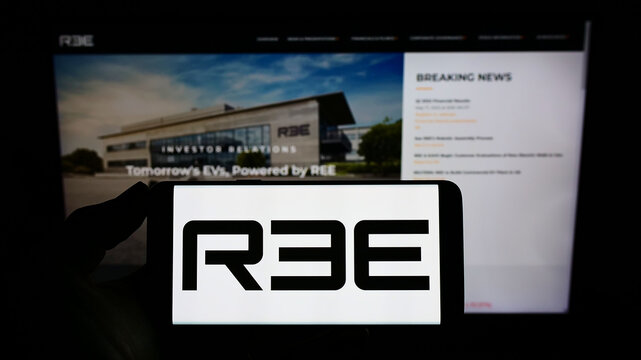 Stuttgart, Germany - 05-20-2022: Person holding mobile phone with logo of Israeli company REE Automotive Ltd. on screen in front of business web page. Focus on phone display.