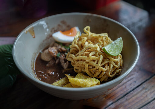 Crispy fried yellow egg noodles in thicken soup added blood with Pork balls, Sliced pork, Sliced bael eggs, Sliced lime and Crispy wonton (Nam tok egg noodles) Thai Boat noodles soup or Guay tiew reua