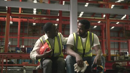 Tired worker man sit in warehouses worried taking break with friend from hard work thinking of production problems at factory, colleague encourage, engineering working in heavy industry factory