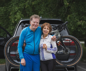 Fototapeta na wymiar Environmental portrait of senior couple bicyclists in front of there car with; bicycles behind them