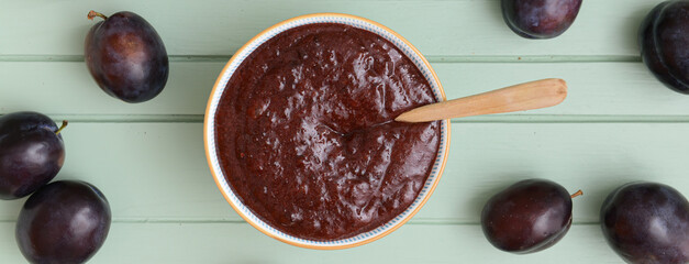 Bowl with delicious homemade plum jam on wooden background