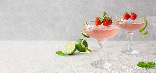 Glasses of tasty cosmopolitan cocktail on light background with space for text