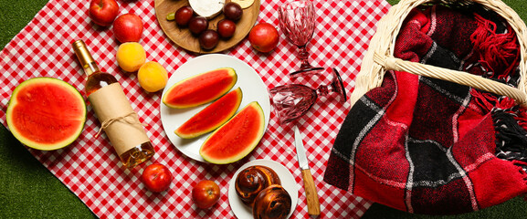 Tasty food and wine for picnic on plaid, top view