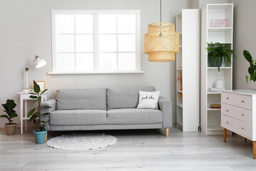 Interior of modern living room with comfortable sofa, lamp and houseplant