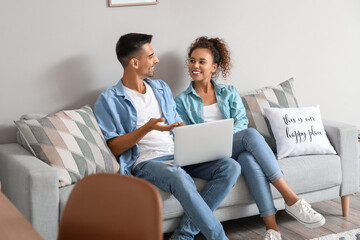 Young couple with laptop video chatting on sofa at home