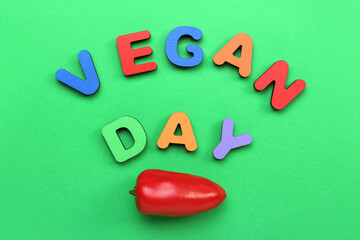 Text VEGAN DAY and fresh pepper on green background