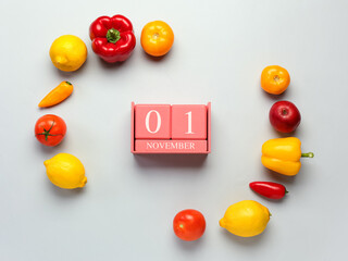 Fresh fruits, vegetables and cube calendar with date NOVEMBER 1 on grey background. World Vegan Day concept
