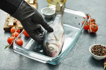 Woman preparing sea bass fish on table